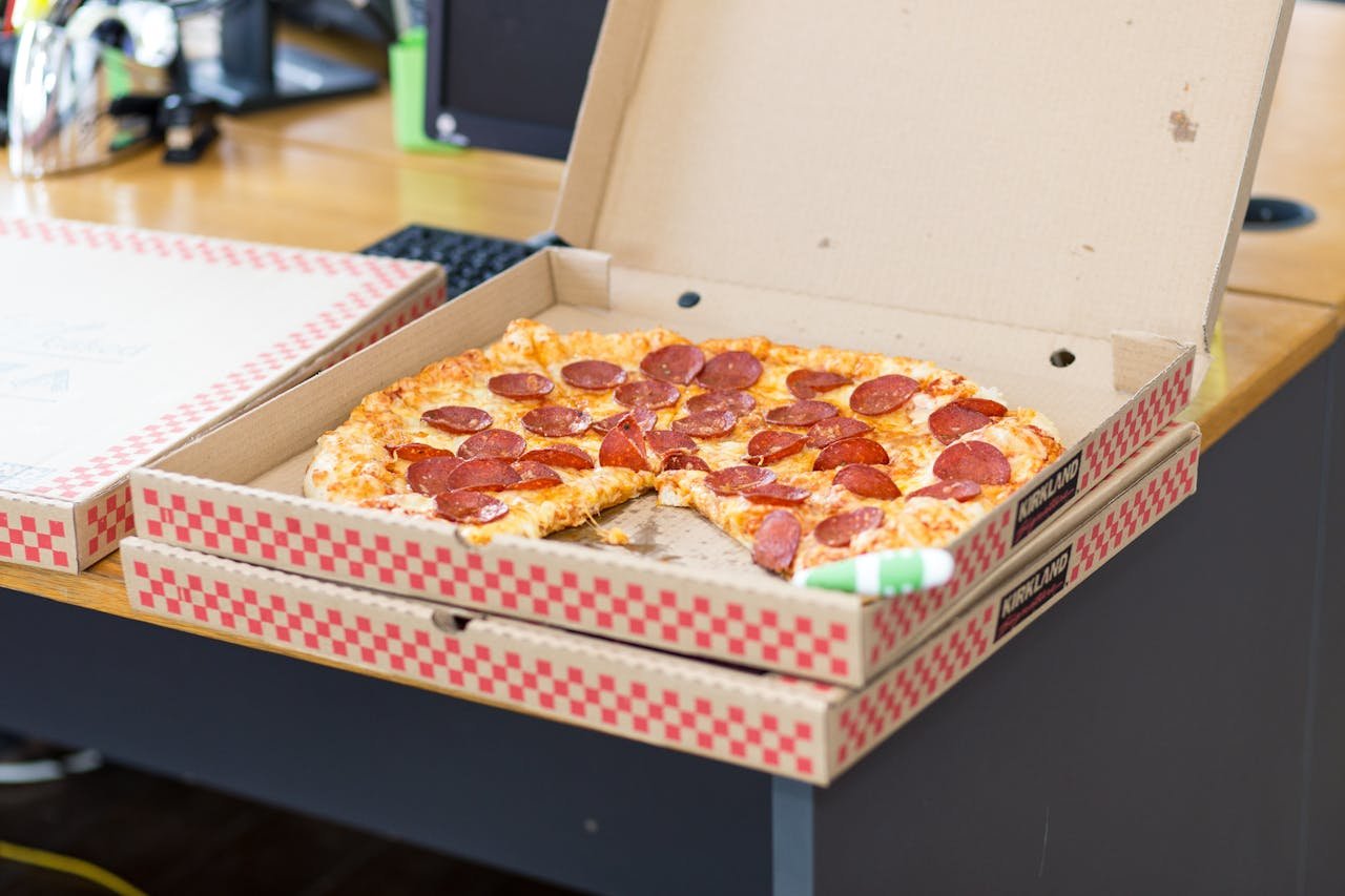 about-02 Delicious pepperoni pizza in an open box on a desk, perfect for a quick meal.